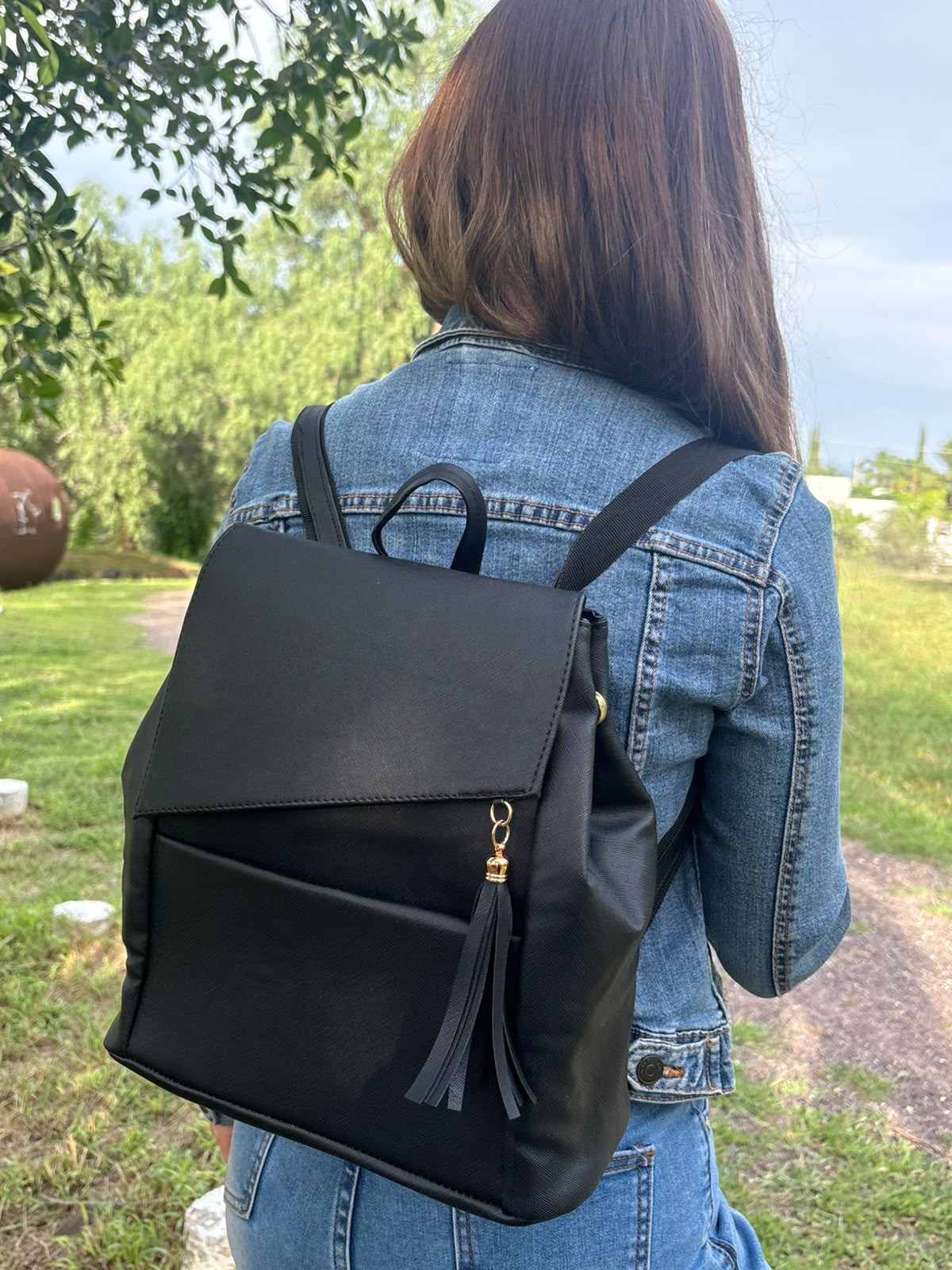Mochila ZAINI negra en textura saffiano, puesta en la espalda de una modelo en exterior